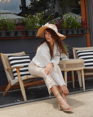 Güzel bir kadın bir kafe 'nin yaz terasında tahta bir sandalyede oturur.