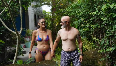 Bir adam ve bir kadın güzel bir havuzun önünde neşeyle yürüyorlar..