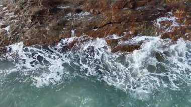 Dev okyanus dalgaları, büyük kaya taşlarıyla boş kumsallara çarpıp köpürüyor.. 