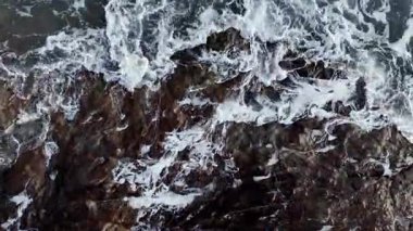 Dev okyanus dalgaları, büyük kaya taşlarıyla boş kumsallara çarpıp köpürüyor.. 