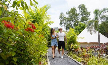 Bir erkek ve bir kadın rahatça Glamping 'de manzaralı bir yolda yürüyor..