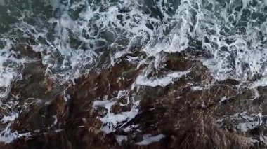 Dev okyanus dalgaları, büyük kaya taşlarıyla boş kumsallara çarpıp köpürüyor.. 