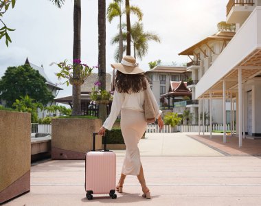 Bagajlı genç kadın yat limanının yanında yürüyor..