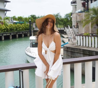 Küçük mavi valizli genç bayan yat limanının yanında yürüyor..