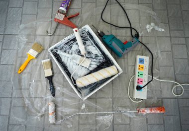 boya silindiri ve tepsi muşamba boya sıçramış fırçalar ve sondaj aleti ve plastik yakın..