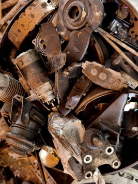 Pile of rusted motor components and gears in cluttered scrap heap.