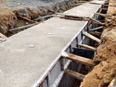 Sıkıştırılmış toprak duvarlar arasında beton dökülen uzun, dar bir siper görünür demir bağlar ve ahşap.