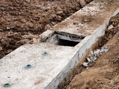 Sıkıştırılmış toprak duvarlar arasında beton dökülen uzun, dar bir siper görünür demir bağlar ve ahşap.
