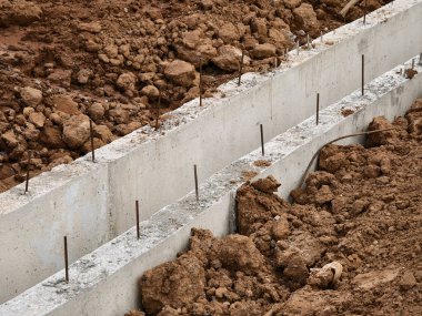 Sıkıştırılmış toprak duvarlar arasında beton dökülen uzun, dar bir siper görünür demir bağlar ve ahşap.