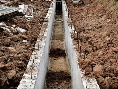 Sıkıştırılmış toprak duvarlar arasında beton dökülen uzun, dar bir siper görünür demir bağlar ve ahşap.