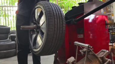 Tamirci kırmızı lastik değiştiricisinde araba lastiği değiştiriyor..