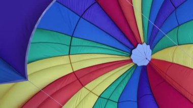 Parlak gökkuşağı paraşütü okyanus üzerinde gökyüzünü dolduruyor.