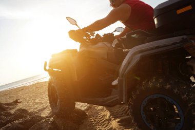 Bir adam sabahın erken saatlerinde kumsalda ekstrem bir ATV 'ye biniyor..