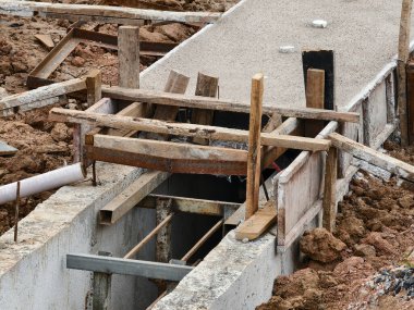 Sıkıştırılmış toprak duvarlar arasında beton dökülen uzun, dar bir siper görünür demir bağlar ve ahşap.