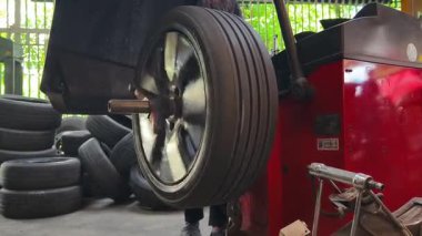 Tamirci kırmızı lastik değiştiricisinde araba lastiği değiştiriyor..