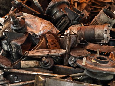 Paslanmış motor bileşenleri ve dağınık hurda yığını..
