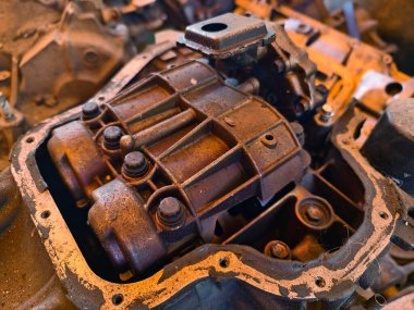 Paslanmış motor parçaları ve paslanmış dişliler kumlu zemine saçılmış..