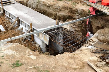 Sıkıştırılmış toprak duvarlar arasında beton dökülen uzun, dar bir siper görünür demir bağlar ve ahşap.