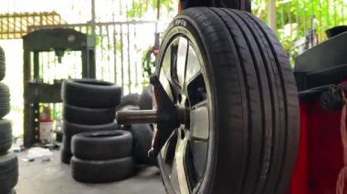 Tamirci kırmızı lastik değiştiricisinde araba lastiği değiştiriyor..