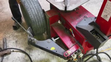 Tamirci kırmızı lastik değiştiricisinde araba lastiği değiştiriyor..
