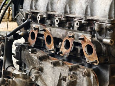 Paslanmış motor parçaları ve paslanmış dişliler kumlu zemine saçılmış..