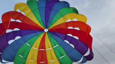 Parlak gökkuşağı paraşütü okyanus üzerinde gökyüzünü dolduruyor.