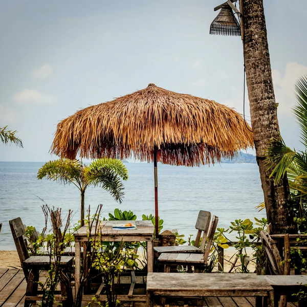 Strohschirm mit Tisch am Strand — Stockfoto