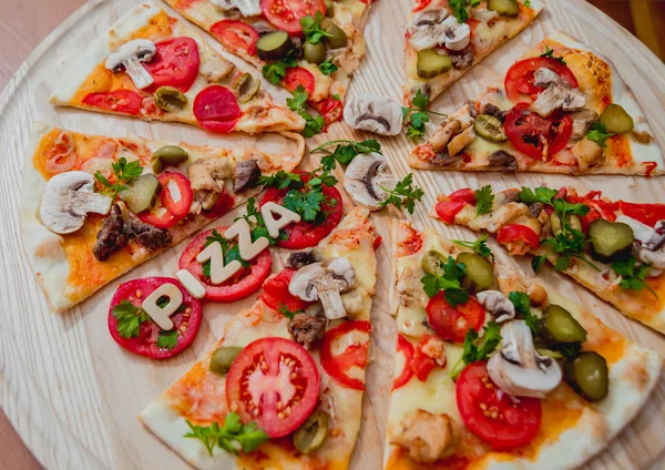 Bitar av pizza med trä bokstäver och tomater — Stockfoto