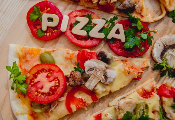 Trozos de pizza con letras de madera y tomates —  Fotos de Stock