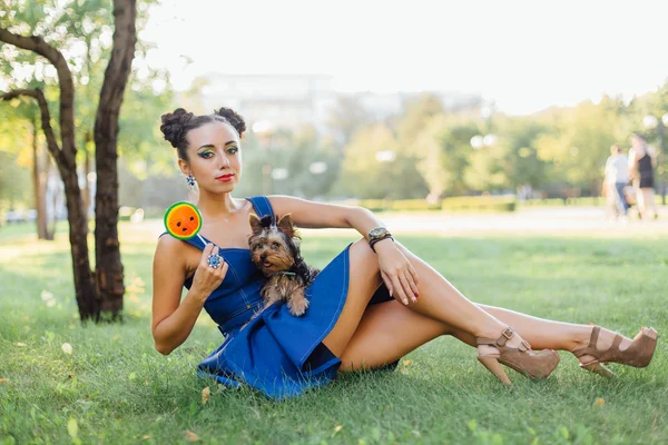 Helles Make-up schönes Mädchen mit yorkshire terrier sitzen auf dem Gras hält Wassermelonen-Lutscher. — Stockfoto