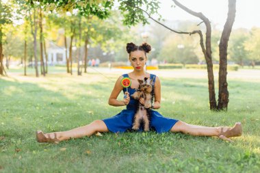 Parlak makyaj Yorkshire Terrier oturma karpuz lolipop tutan çim ile güzel kız. 