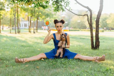 Parlak makyaj Yorkshire Terrier oturma karpuz lolipop tutan çim ile güzel kız. 