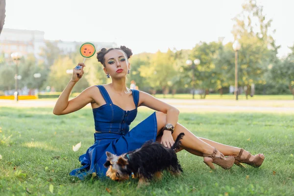 Helles Make-up schönes Mädchen mit yorkshire terrier sitzen auf dem Gras hält Wassermelonen-Lutscher. — Stockfoto