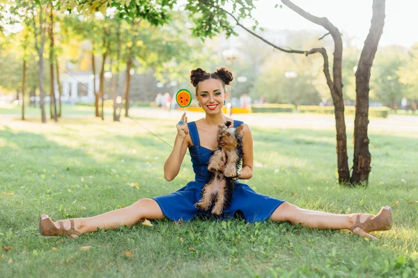 Helles Make-up schönes Mädchen mit yorkshire terrier sitzen auf dem Gras hält Wassermelonen-Lutscher. — Stockfoto