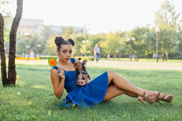 Maquiagem brilhante menina bonita com Yorkshire Terrier assentos na grama segurando pirulito melancia . — Fotografia de Stock