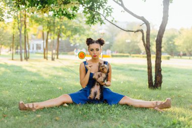 Parlak makyaj Yorkshire Terrier oturma karpuz lolipop tutan çim ile güzel kız. 