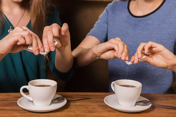 한 잔의 커피에 설탕을 넣어 두 여자의 손 — 스톡 사진