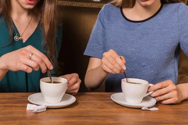 手中两个女人把糖放在一杯咖啡 — 图库照片