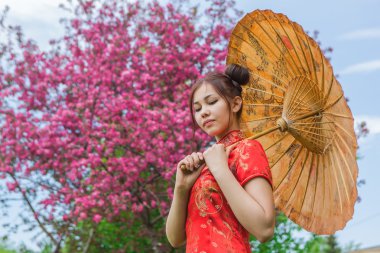 Güzel Asyalı kız geleneksel Çince kırmızı elbise ile bambu şemsiye.