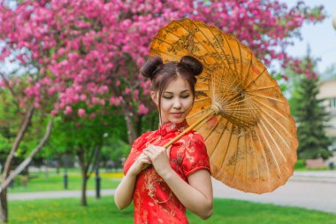 Güzel Asyalı kız geleneksel Çince kırmızı elbise ile bambu şemsiye.