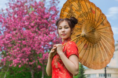 Güzel Asyalı kız geleneksel Çince kırmızı elbise ile bambu şemsiye.