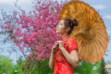 Güzel Asyalı kız geleneksel Çince kırmızı elbise ile bambu şemsiye.