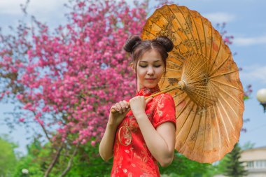 Güzel Asyalı kız geleneksel Çince kırmızı elbise ile bambu şemsiye.