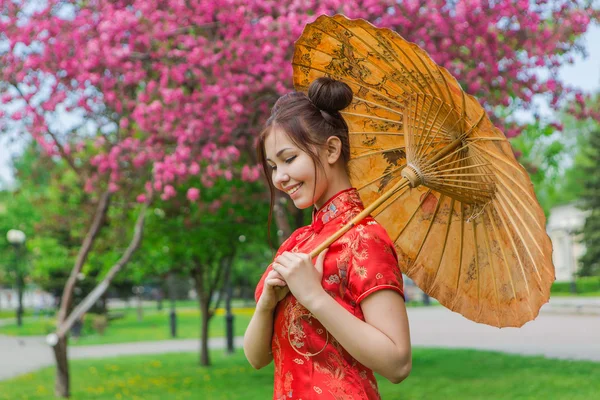 Menina asiática bonita em vestido vermelho chinês tradicional com guarda-chuva de bambu . — Fotografia de Stock