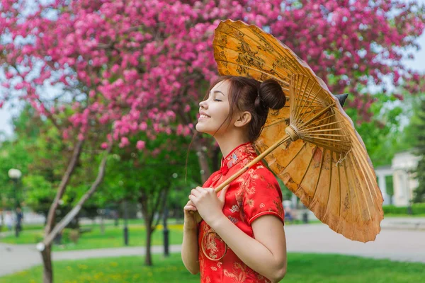 Vackra asiatiska flicka i traditionell kinesiska röda klänning med bambu paraply. — Stockfoto