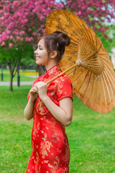 Vackra asiatiska flicka i traditionell kinesiska röda klänning med bambu paraply. — Stockfoto