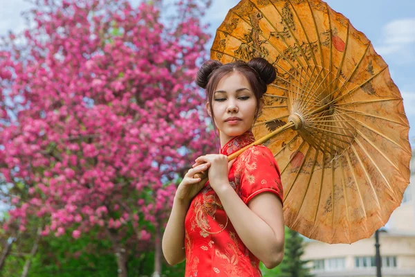 Hermosa chica asiática en vestido rojo chino tradicional con paraguas de bambú . — Foto de Stock