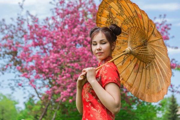 Vackra asiatiska flicka i traditionell kinesiska röda klänning med bambu paraply. — Stockfoto