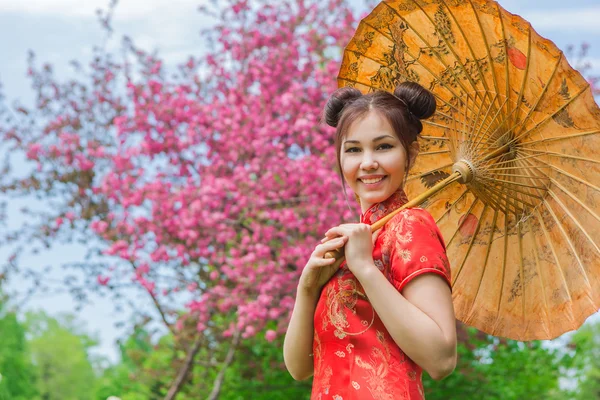 Beautiful asian girl in traditional chinese red dress with bamboo umbrella. — Stock Photo, Image