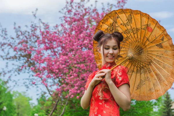 Vackra asiatiska flicka i traditionell kinesiska röda klänning med bambu paraply. — Stockfoto